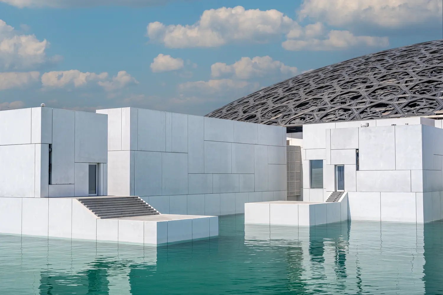 Bílé budovy a kopule Louvre Abu Dhabi nad vodou